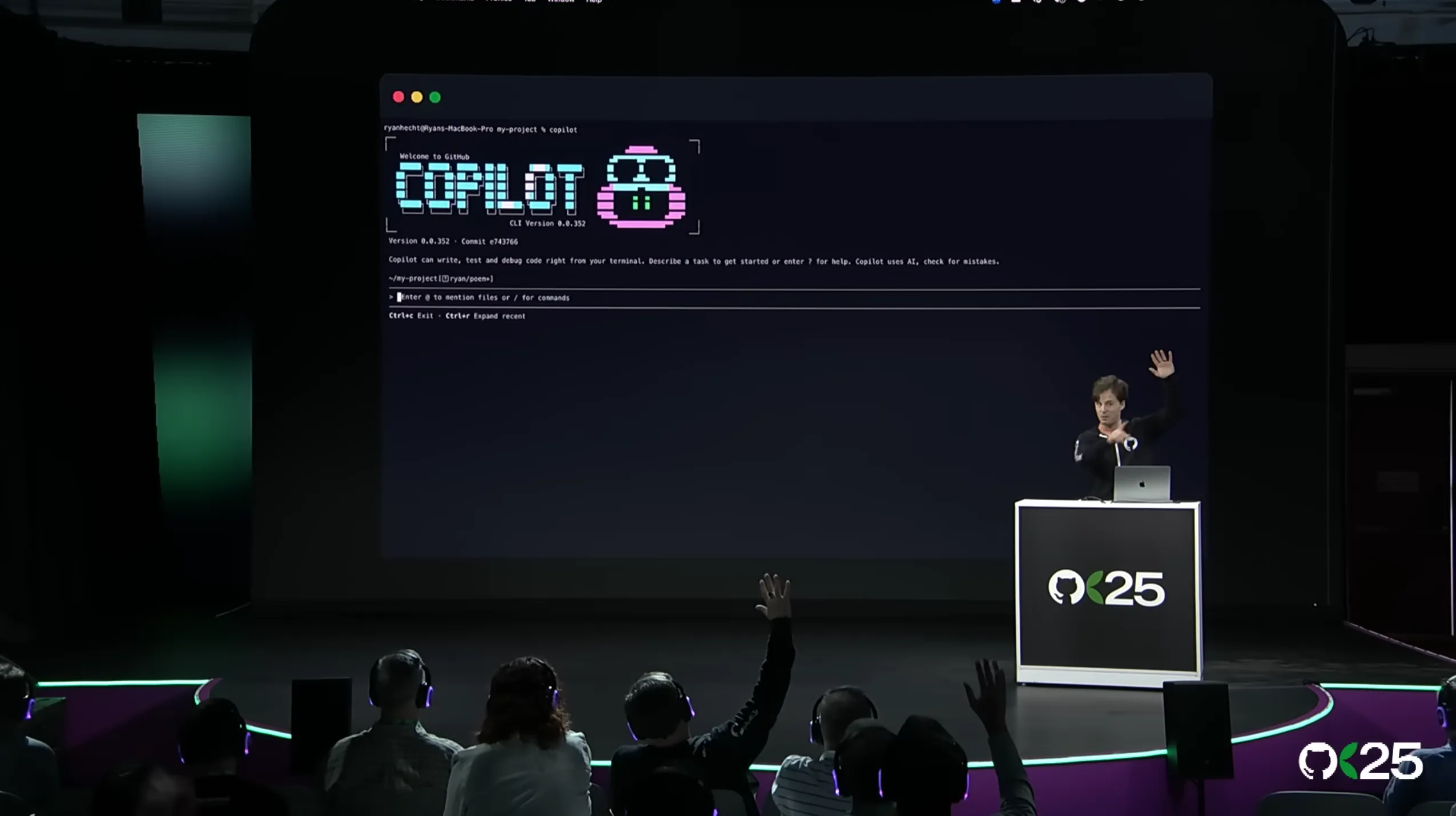 Ryan Hecht presenting GitHub Copilot CLI on the GitHub Universe 2025 stage as audience members raise their hands